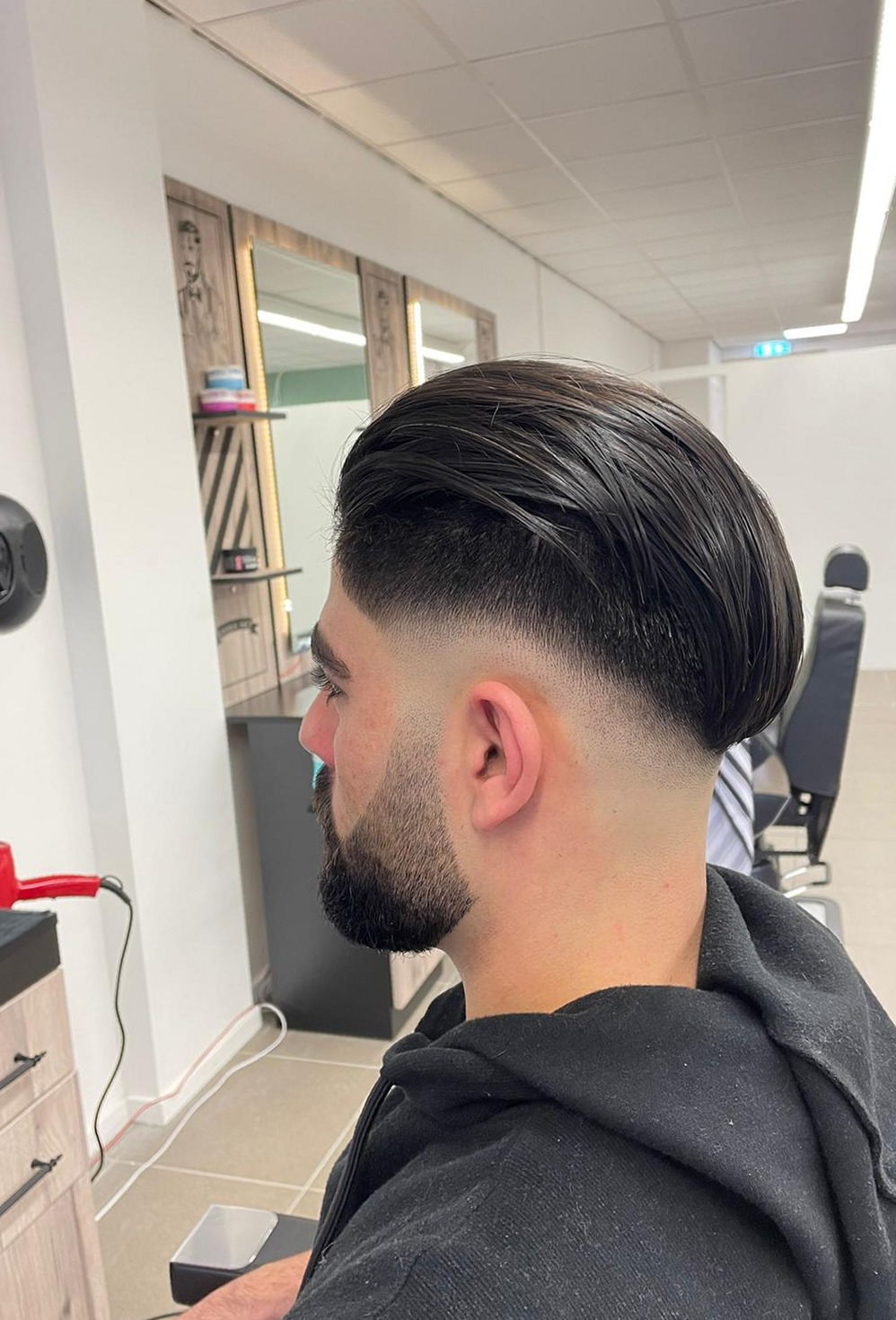 Klant met een strakke fade en volle baard in de stoel bij Bravo kapper